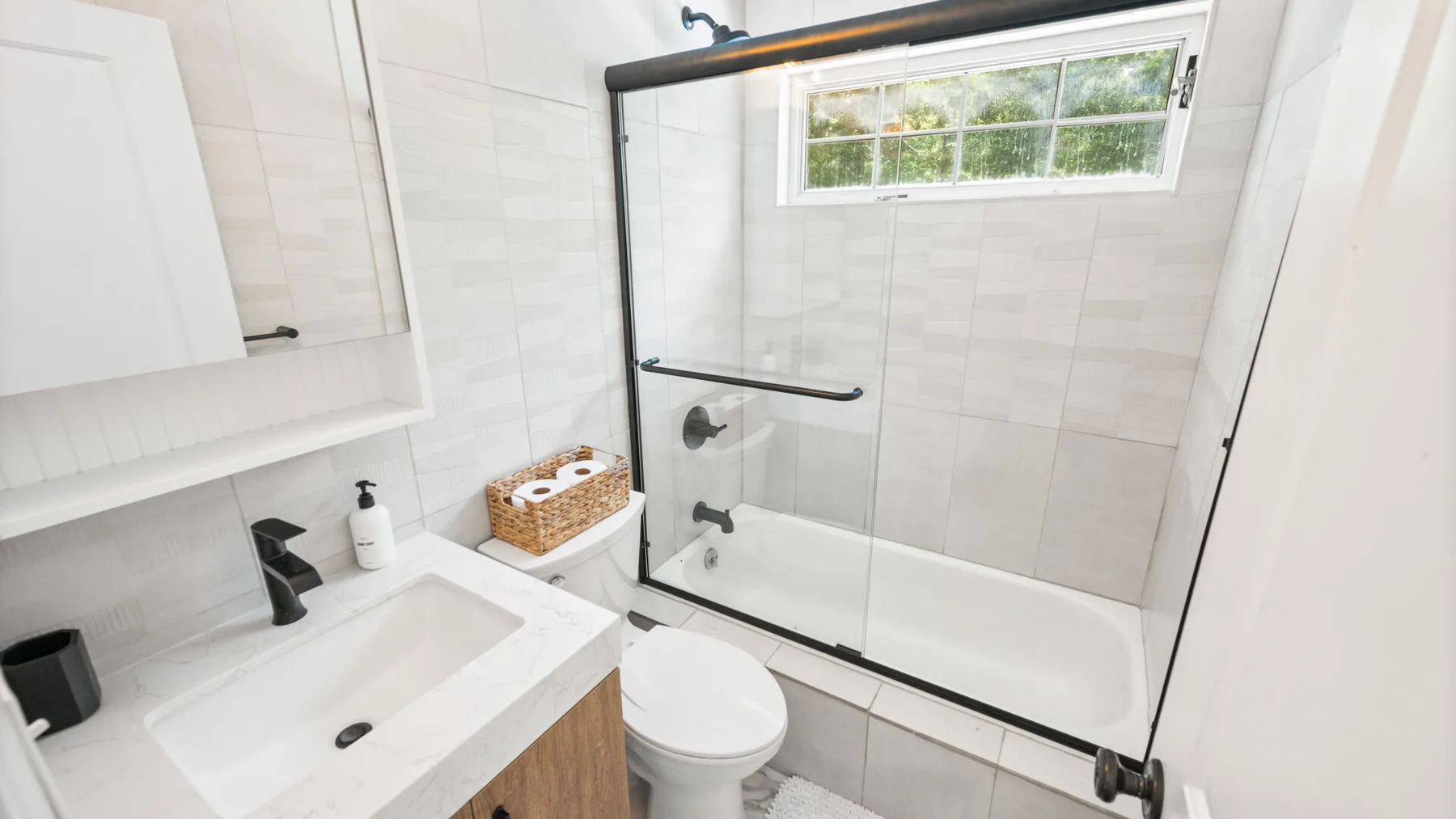 Un baño luminoso con lavabo, inodoro y ducha de vidrio.