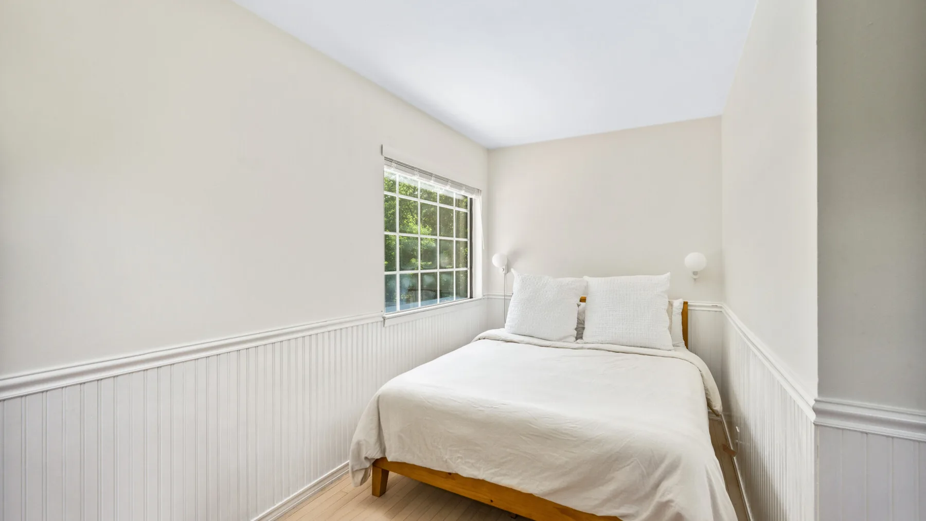 Un dormitorio luminoso con una cama bajo una ventana grande.