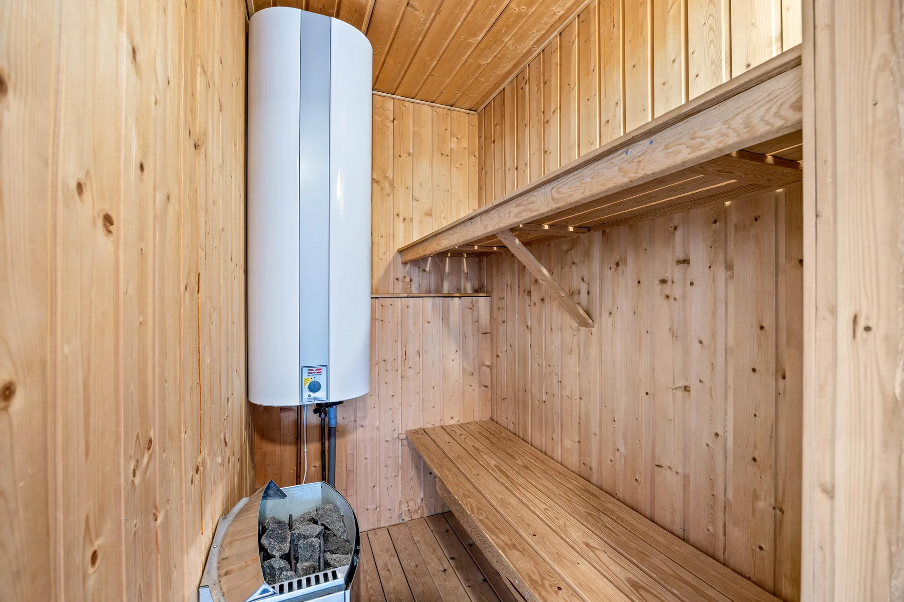 Una sauna revestida de madera con un calentador y un banco largo.