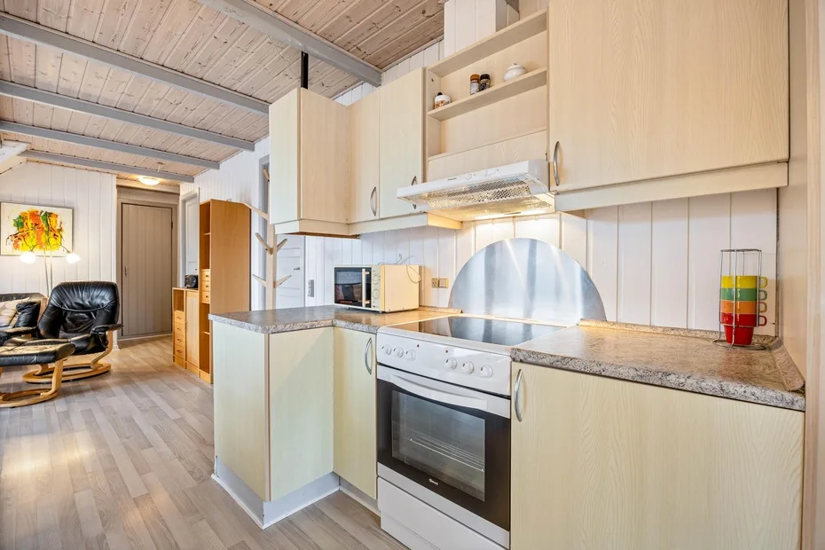 Una cocina con gabinetes de madera clara, una encimera y un horno.