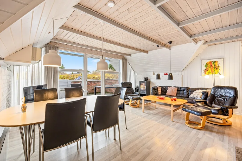 Una luminosa sala de estar y comedor diáfanos con ventanales y una zona de asientos.
