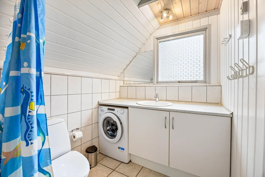 Un baño compacto con una lavadora junto al lavabo y el mueble.