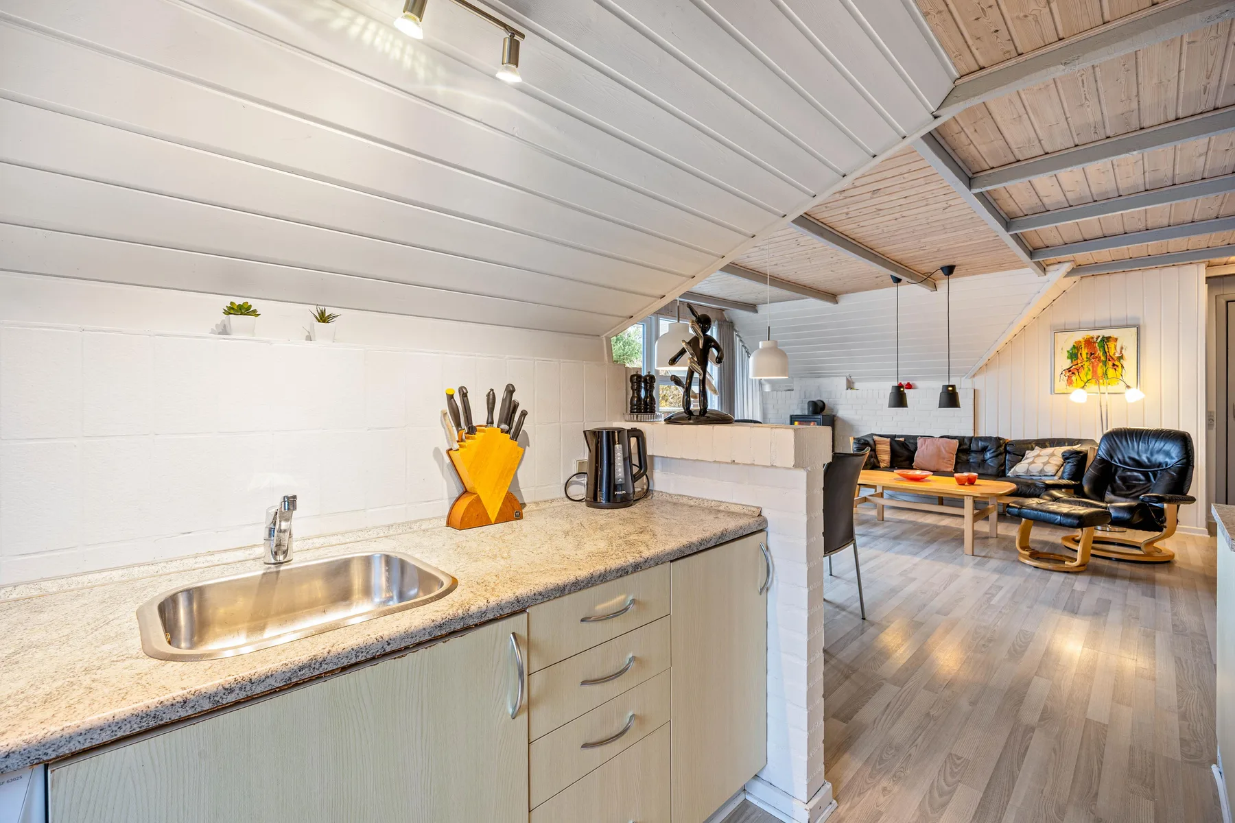 Una encimera de cocina con fregadero se abre a una sala de estar.