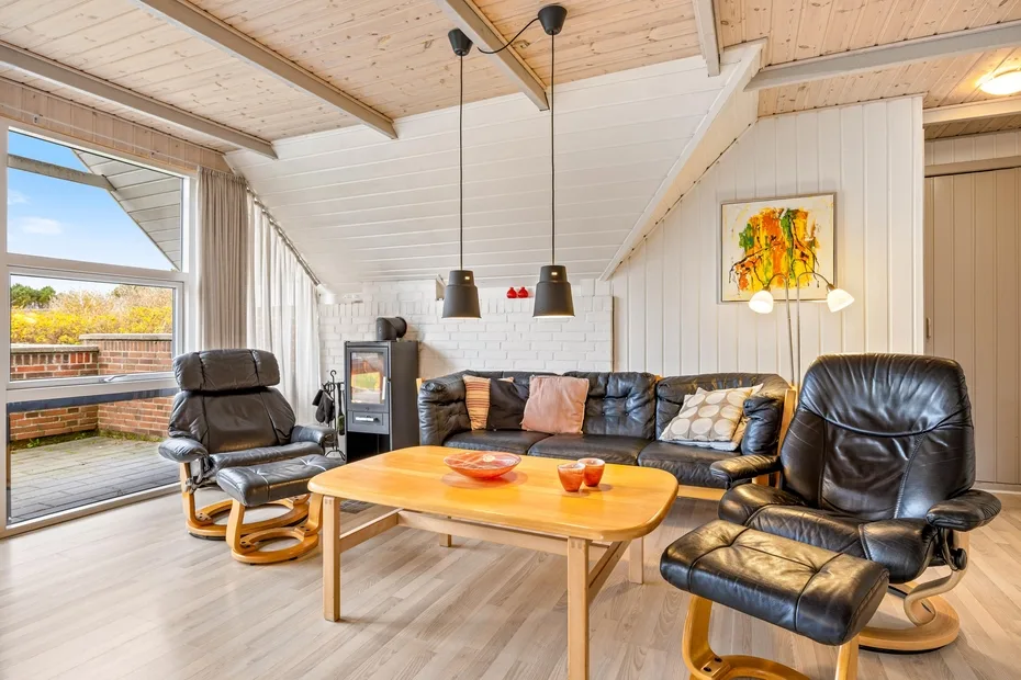 Una sala de estar con asientos alrededor de una mesa de centro de madera y grandes ventanas.