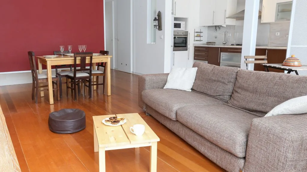 Sala de estar y comedor con sofá, mesa de centro y cocina al fondo.
