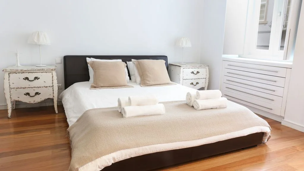 Un dormitorio con una cama bien hecha y mesitas de noche a juego.
