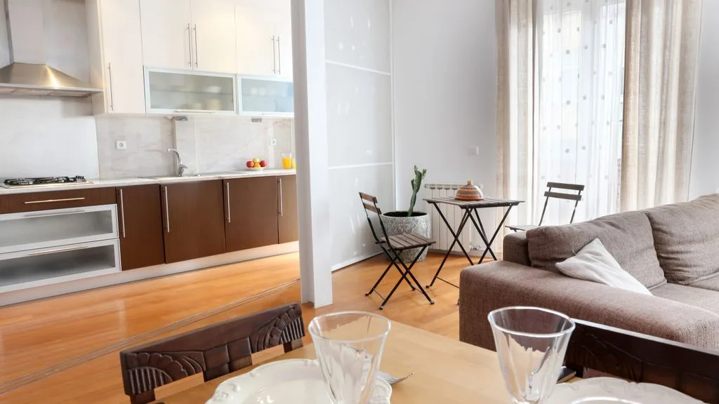 Una luminosa sala de estar abierta con cocina, mesa de comedor y asientos.