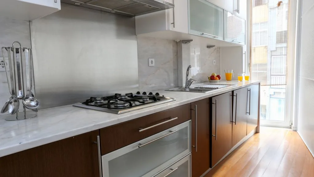 Una cocina moderna con placa de gas, fregadero y ventanales.