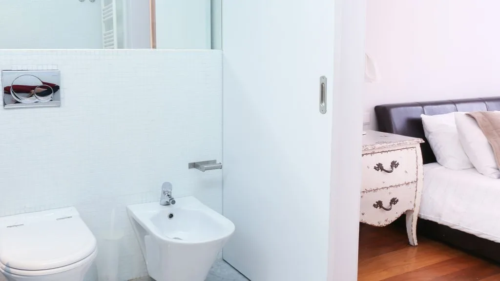 Un baño con inodoro y bidé junto a un dormitorio.