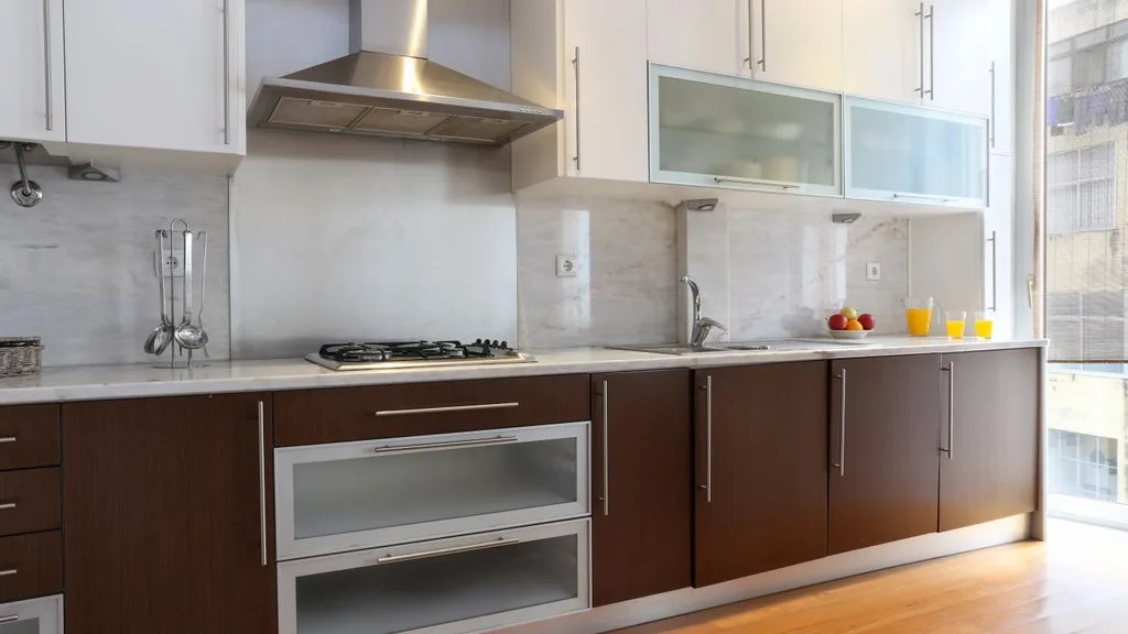 Una cocina luminosa con gabinetes inferiores oscuros y una encimera larga.