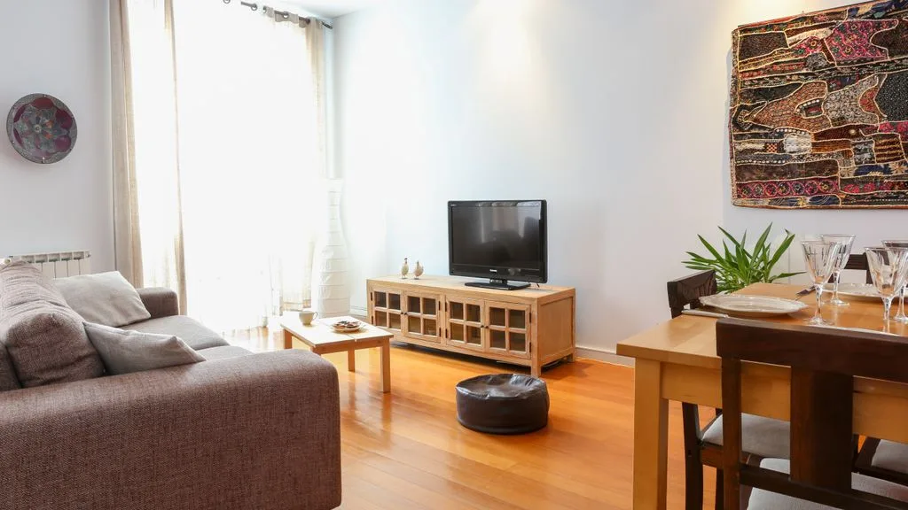 Una sala luminosa con asientos, un televisor y una mesa de comedor.