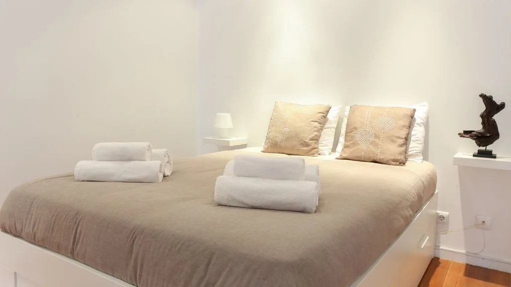 Un dormitorio con una cama hecha y toallas dobladas.