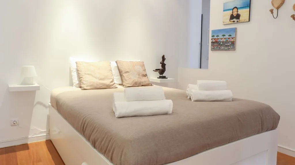 Un dormitorio con una cama bien arreglada y cuadros en la pared.
