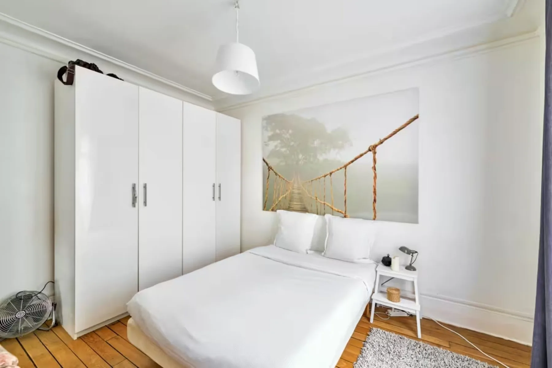 A bright bedroom with a white bed and a large wardrobe.