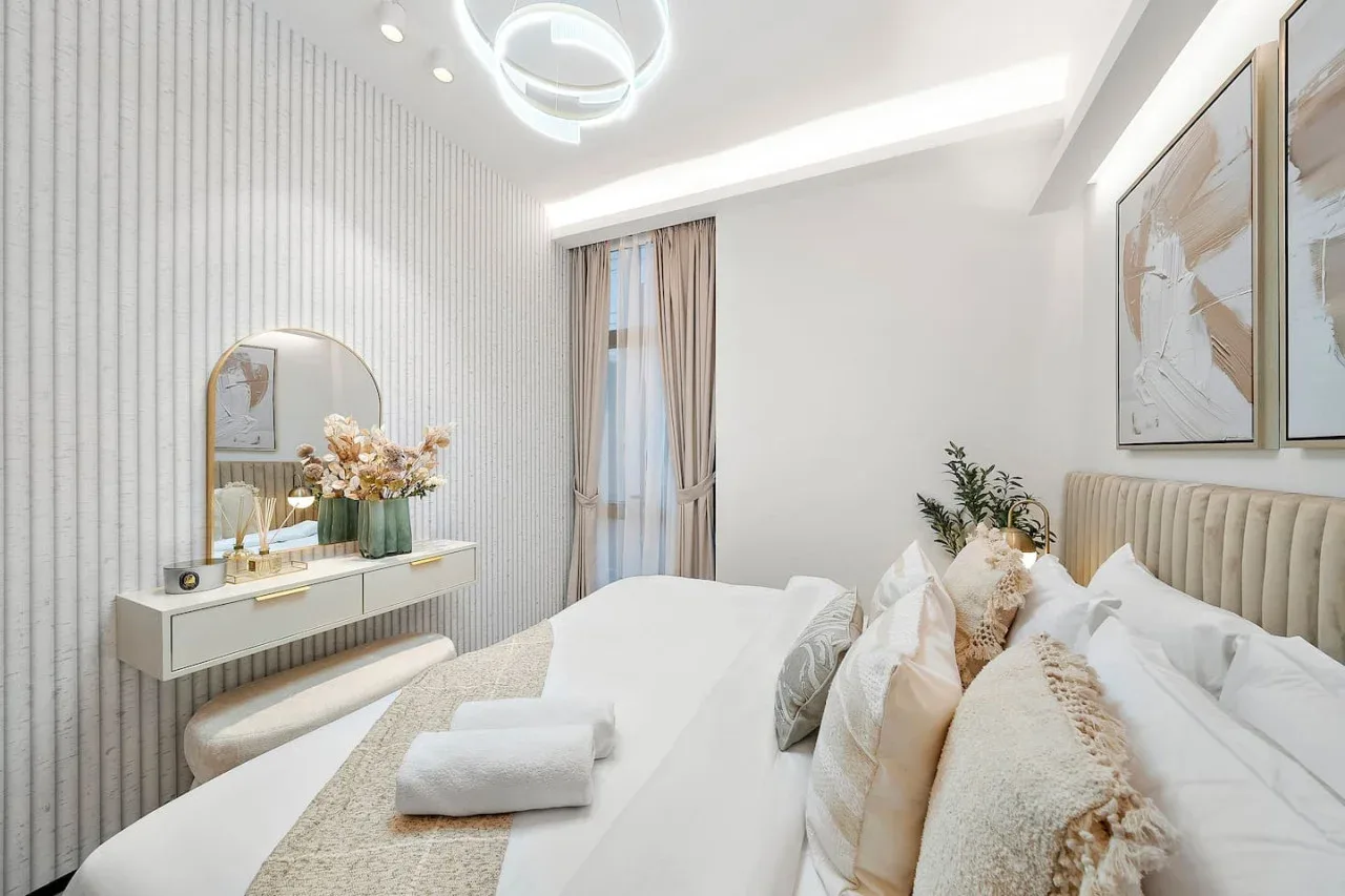 Un dormitorio luminoso con cama, pared a rayas y tocador.