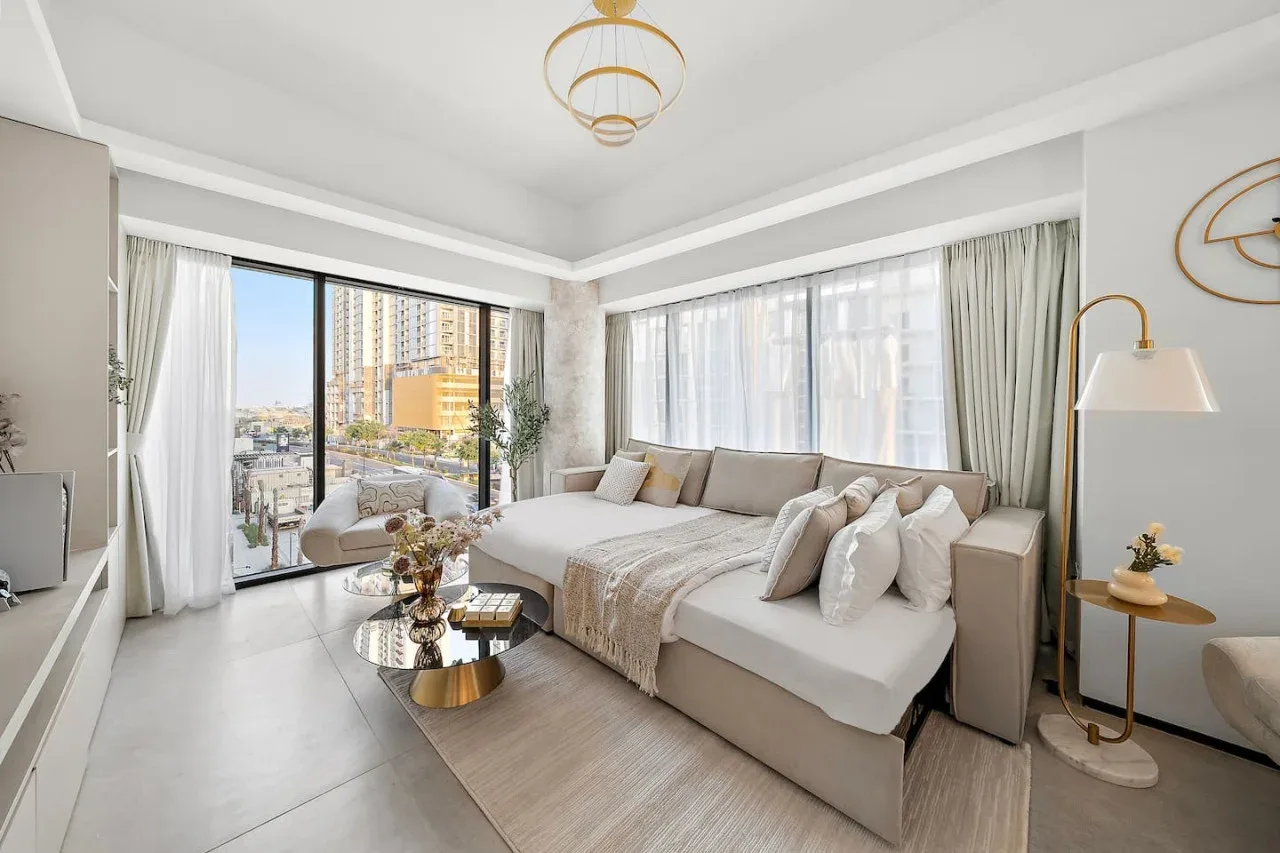 Un dormitorio luminoso con una cama grande, amplias ventanas y una pequeña zona de estar.
