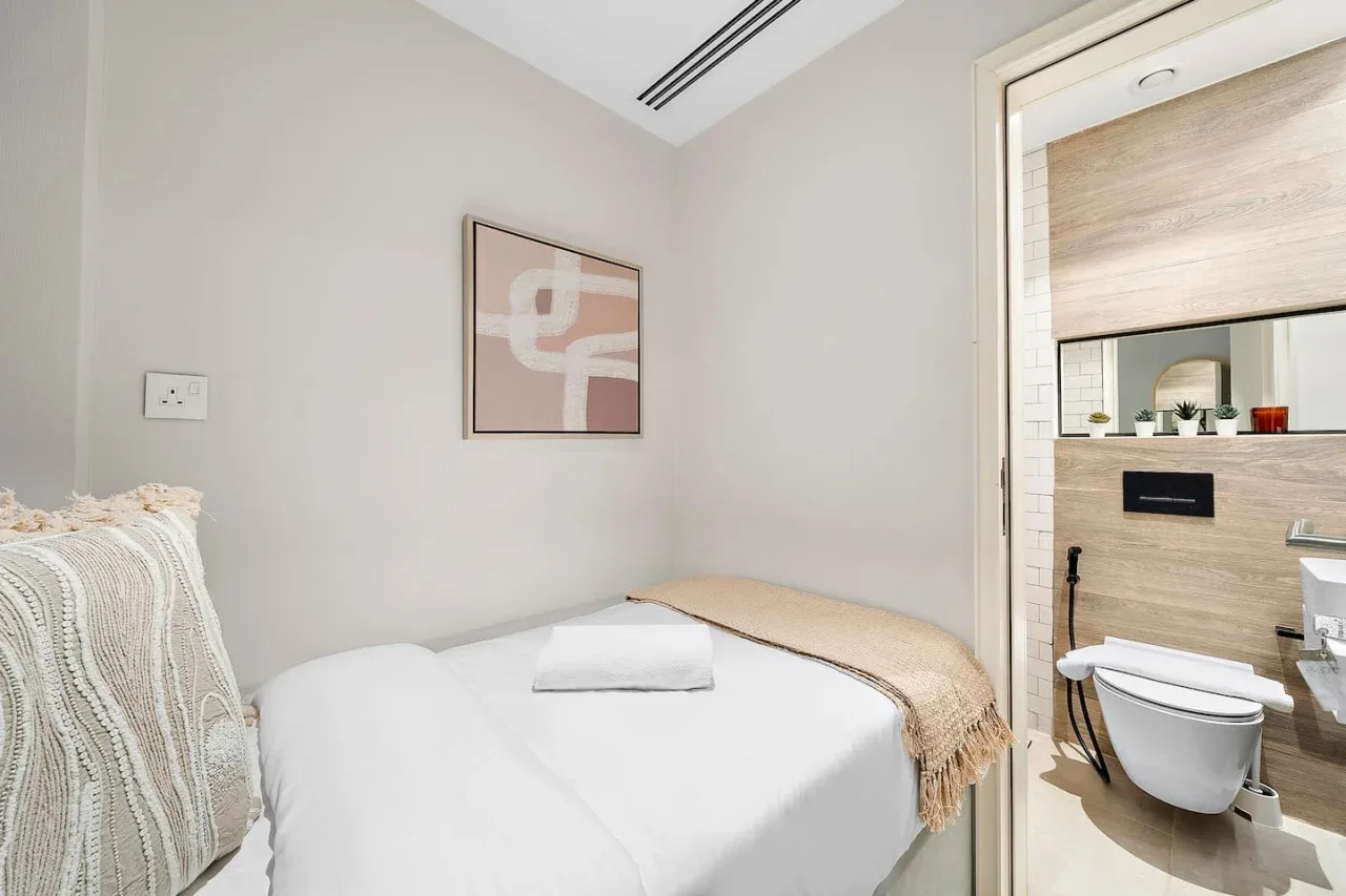Un dormitorio con una cama bien tendida y un baño contiguo.