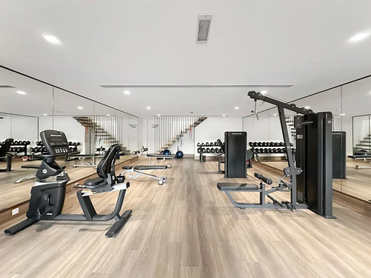 Un gimnasio con espejos, máquinas de ejercicio y pesas.