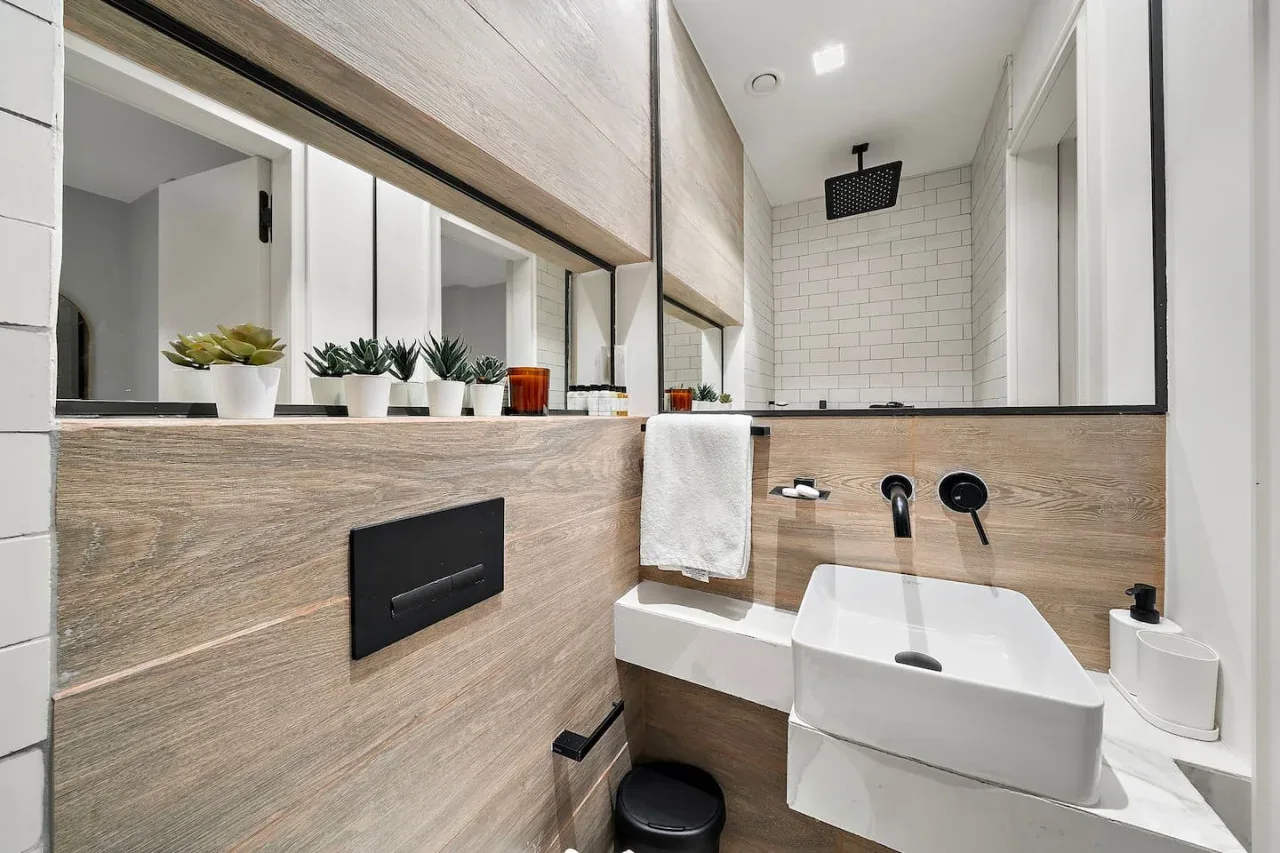 Un baño moderno con una ducha de pared y un lavabo blanco.