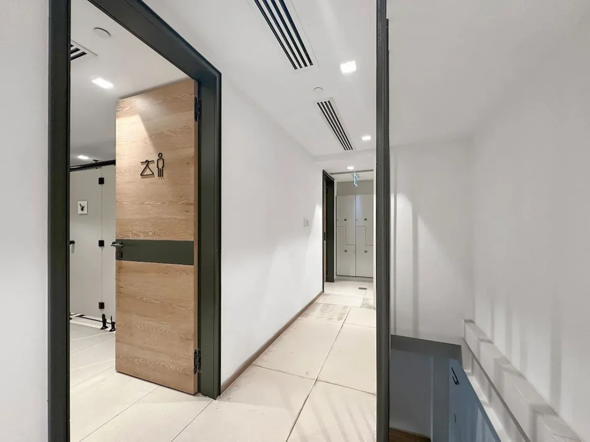 Un pasillo luminoso con la entrada a un baño y una escalera.