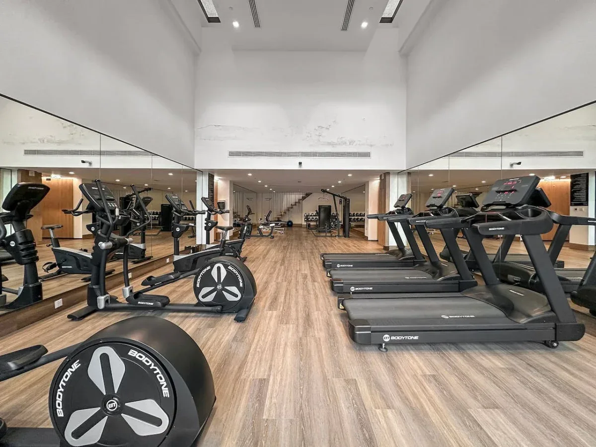 Un gimnasio con cintas de correr, bicicletas estáticas y máquinas de ejercicio.