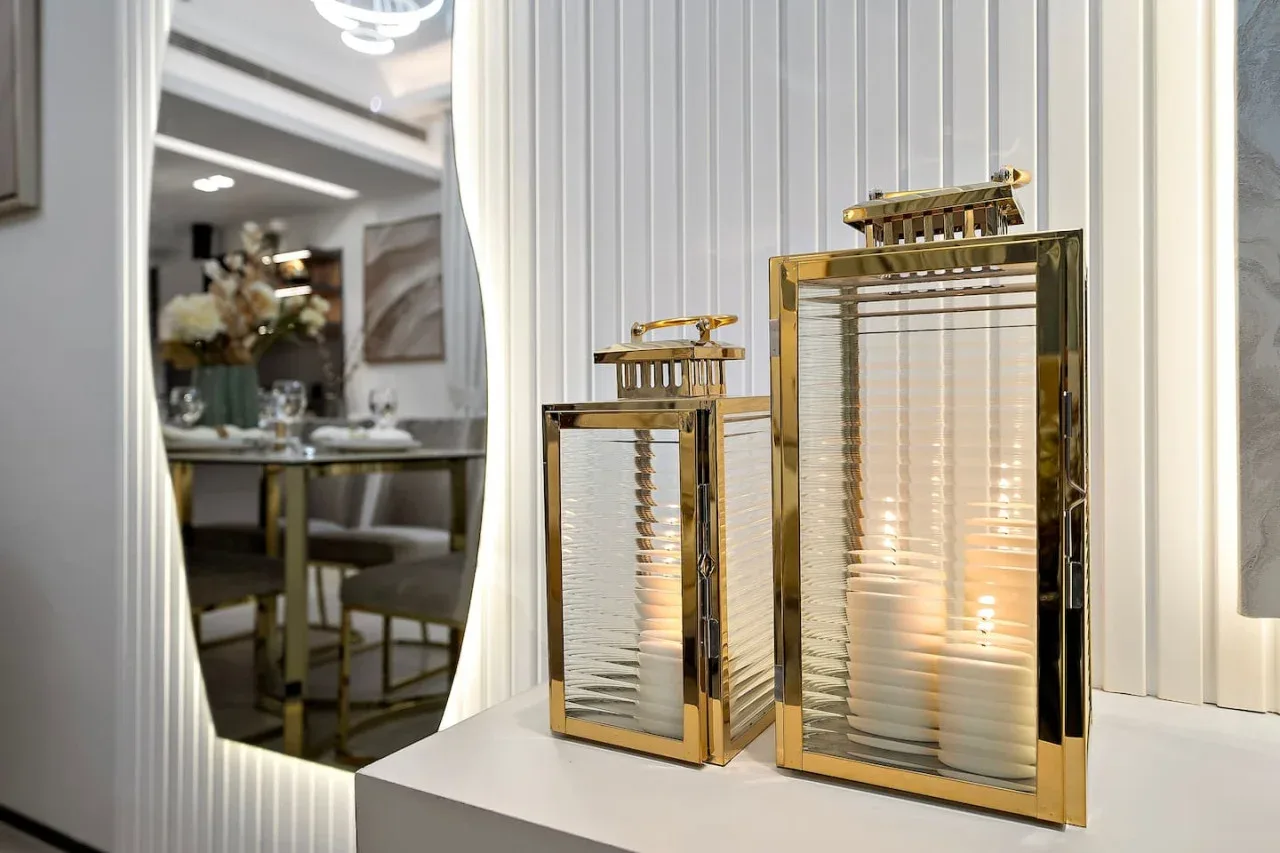 Faroles decorativos están sobre una encimera blanca junto a un comedor abierto.