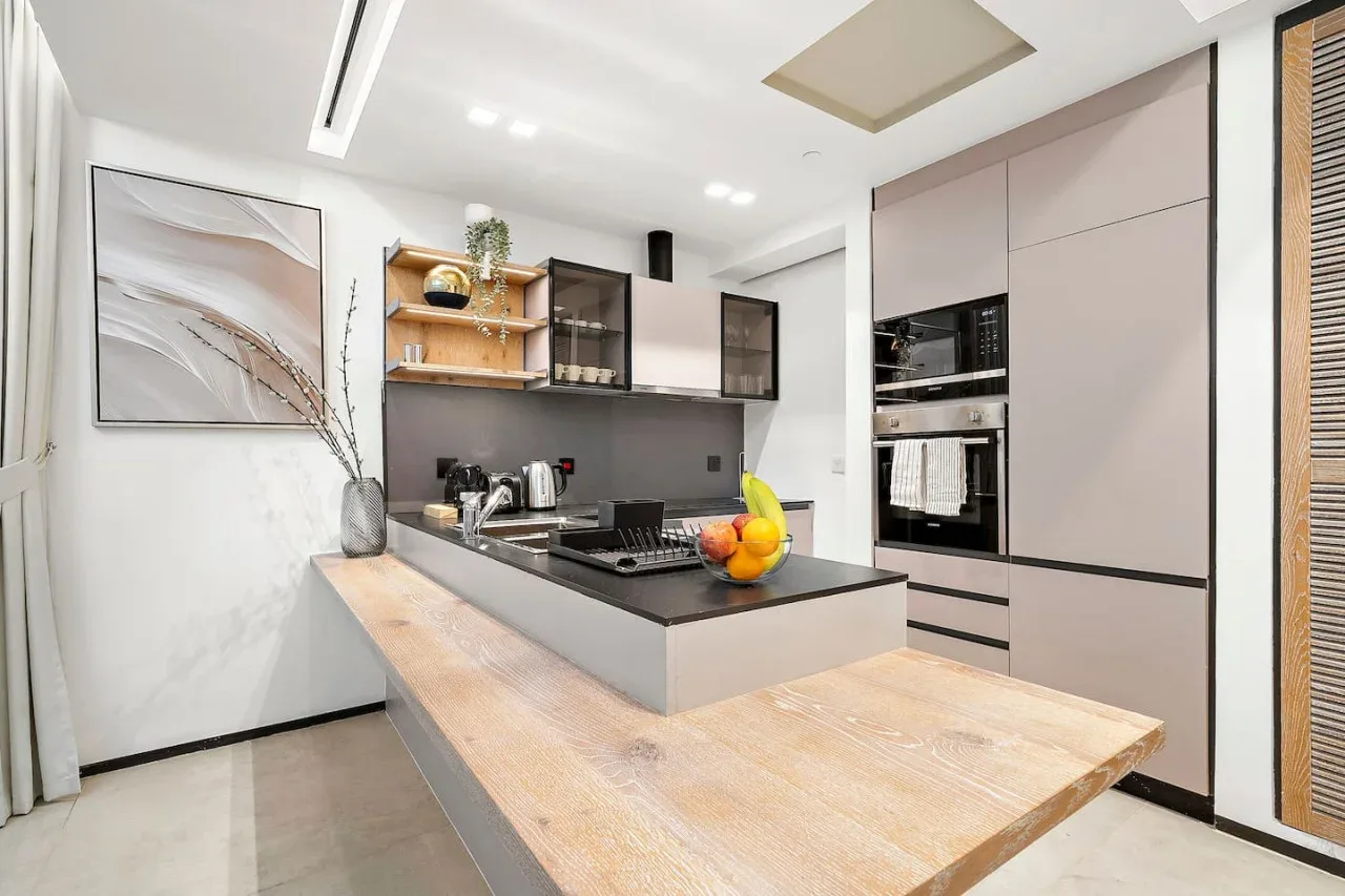 Una cocina moderna con una encimera oscura y una barra de madera clara.