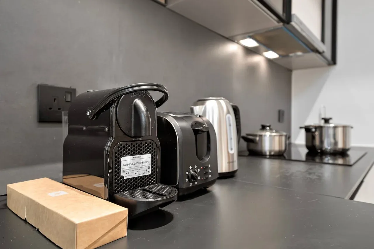 Una encimera de cocina moderna tiene una cafetera, un hervidor y utensilios de cocina.