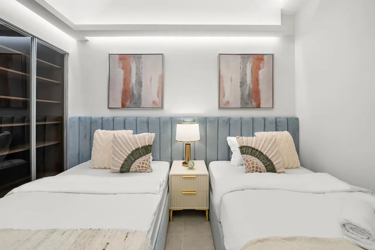 Un dormitorio con dos camas, una mesita compartida y arte abstracto en la pared.