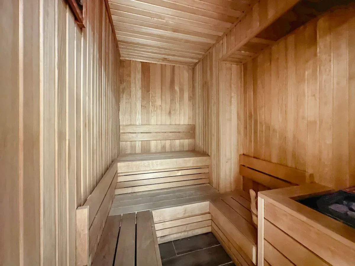 Una sauna de madera con bancos escalonados y un calefactor.