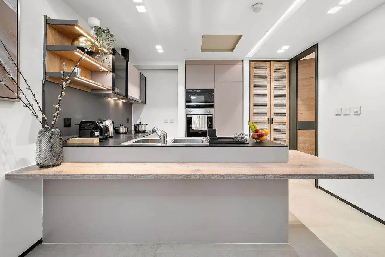 Una cocina moderna con una isla amplia y estantes abiertos.