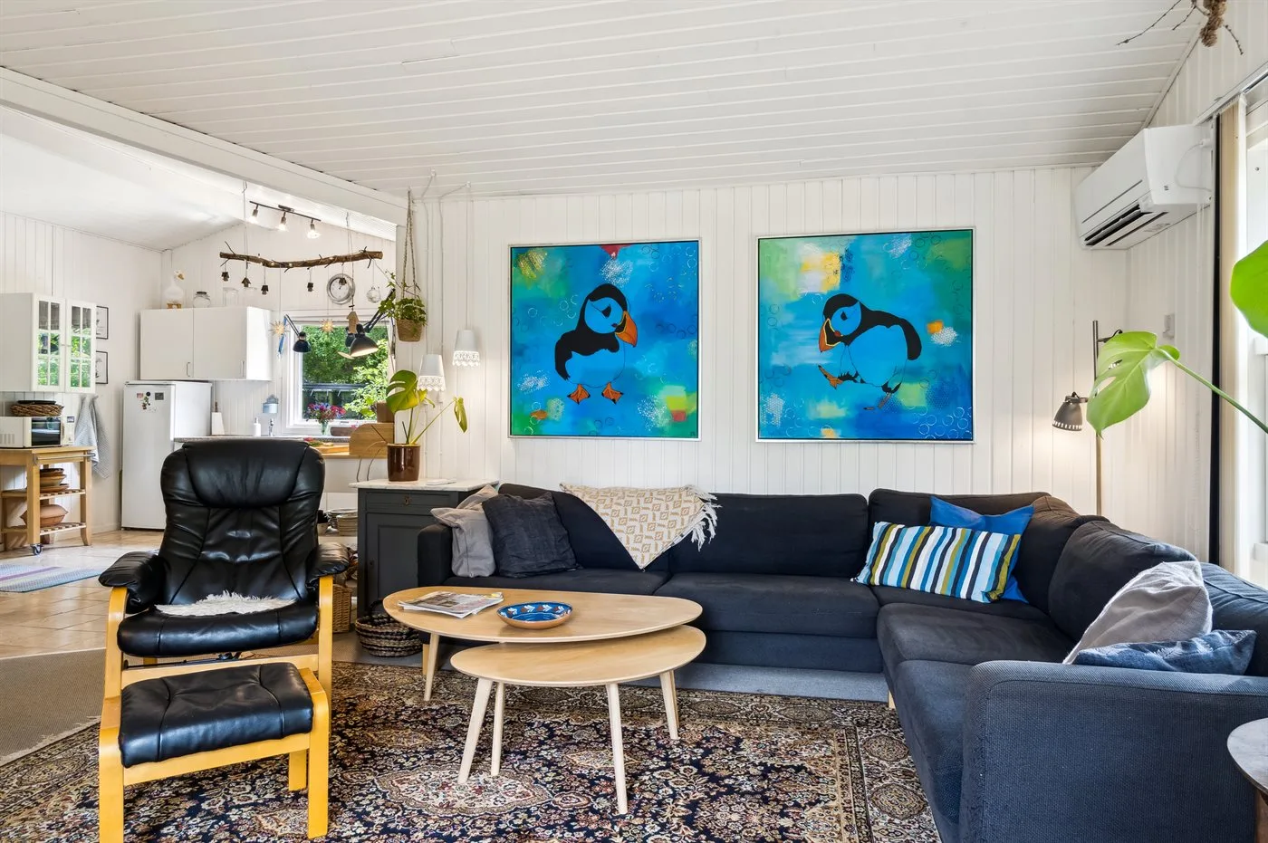 Sala de estar con un sofá y cuadros coloridos en la pared.