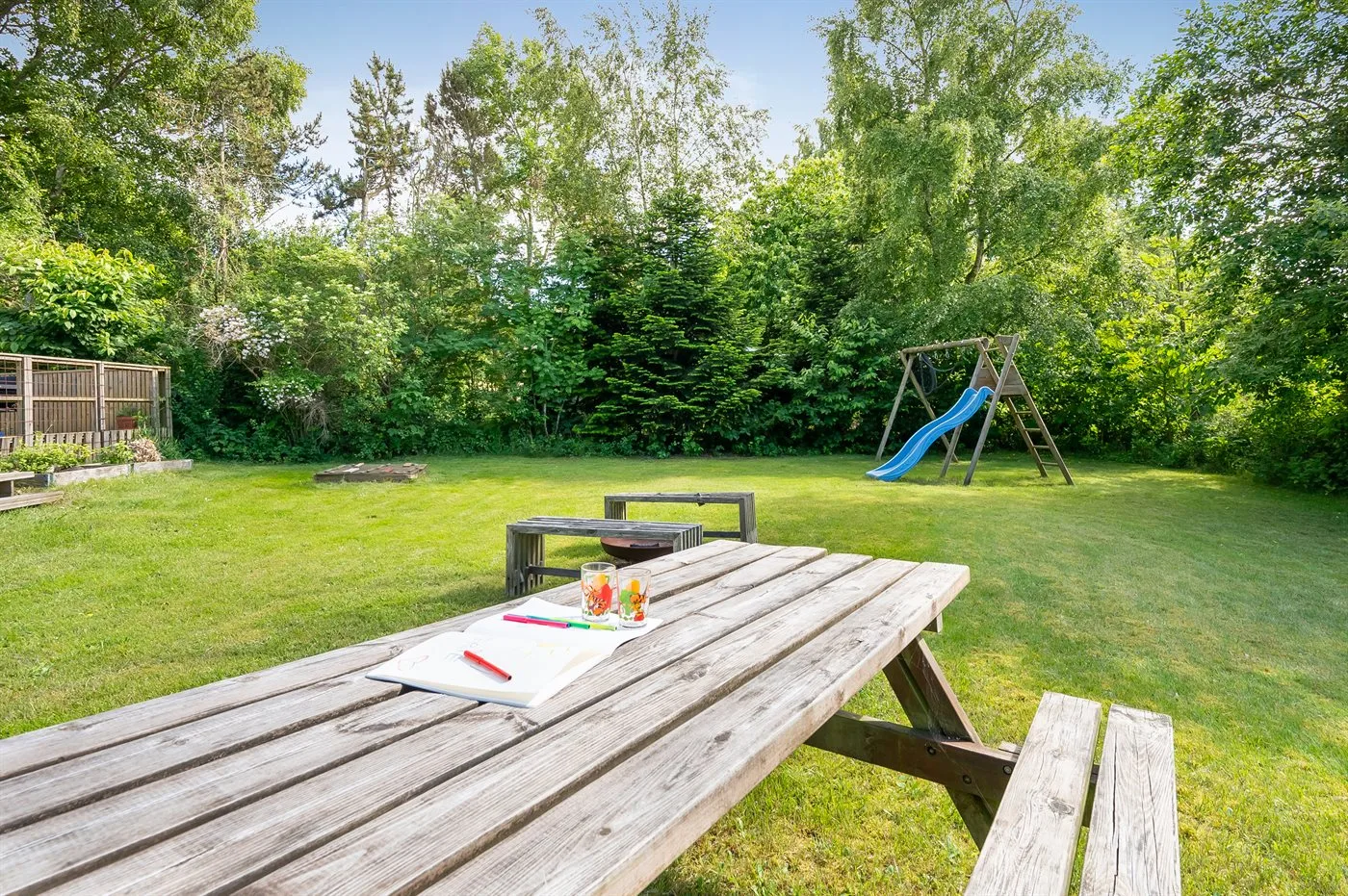 Un patio con césped, una mesa de picnic de madera y una estructura de juego.