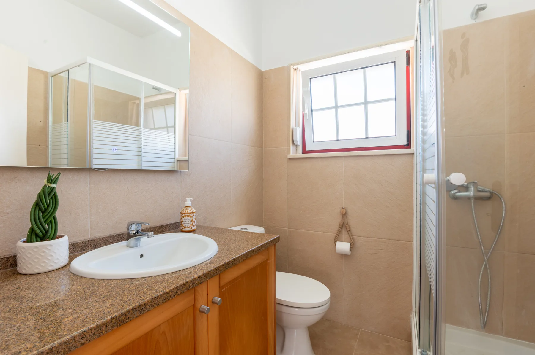 A bathroom with a sink, mirror, toilet, and shower.