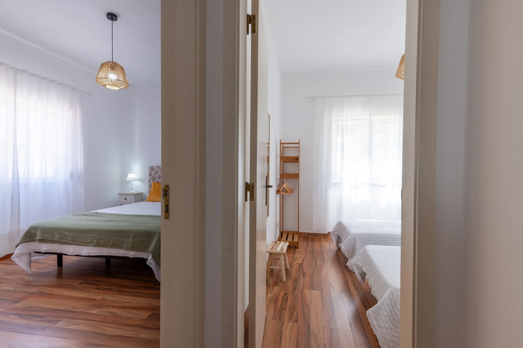 A bedroom with a bed and a window beside a second bedroom.