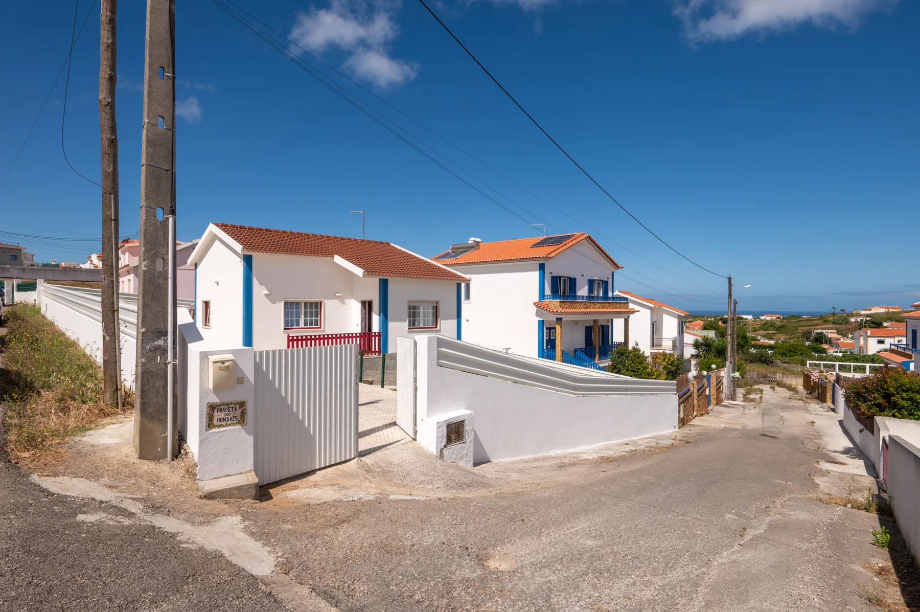 White houses with red-tiled roofs line a sunny residential street.