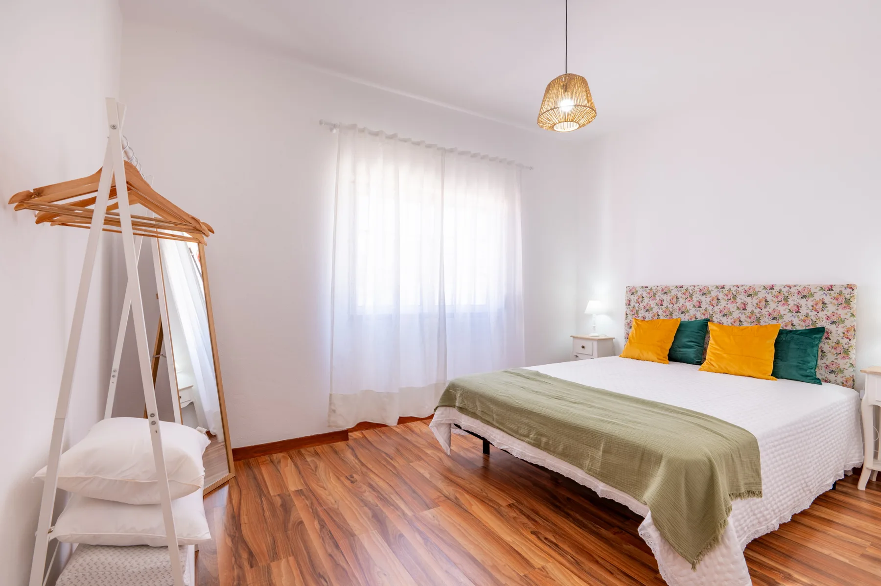 Bedroom with a bed, colorful pillows, and a freestanding clothes rack.