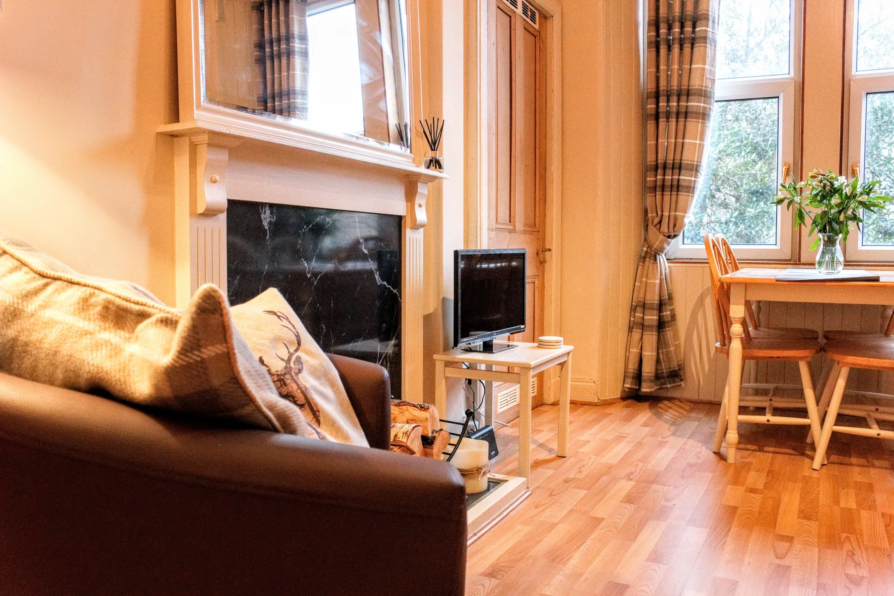 A living room with seating, a fireplace, and a dining table beside the windows.