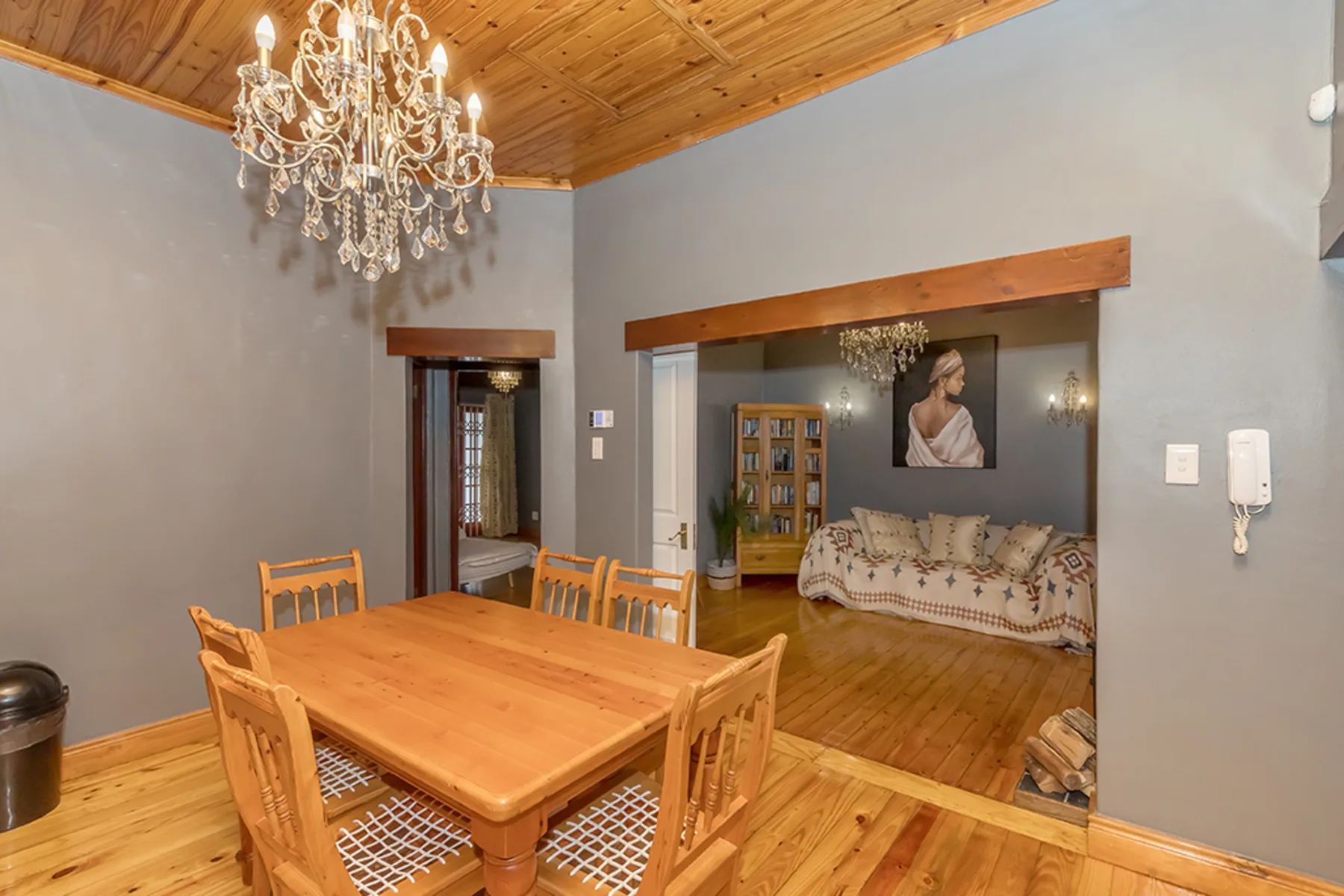 A dining area with a wooden table and chairs beneath a chandelier.
