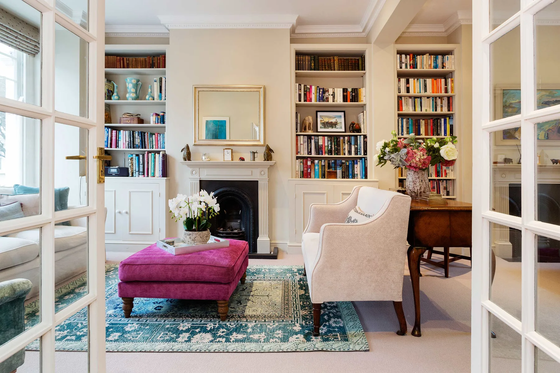 A bright living room with a fireplace, bookshelves, and seating.