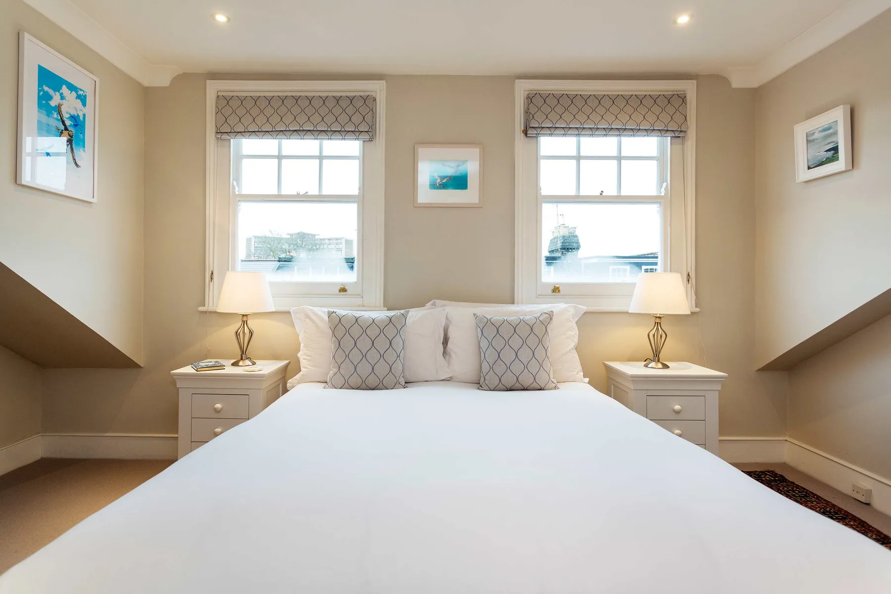 A bright bedroom with a bed centered between two windows.