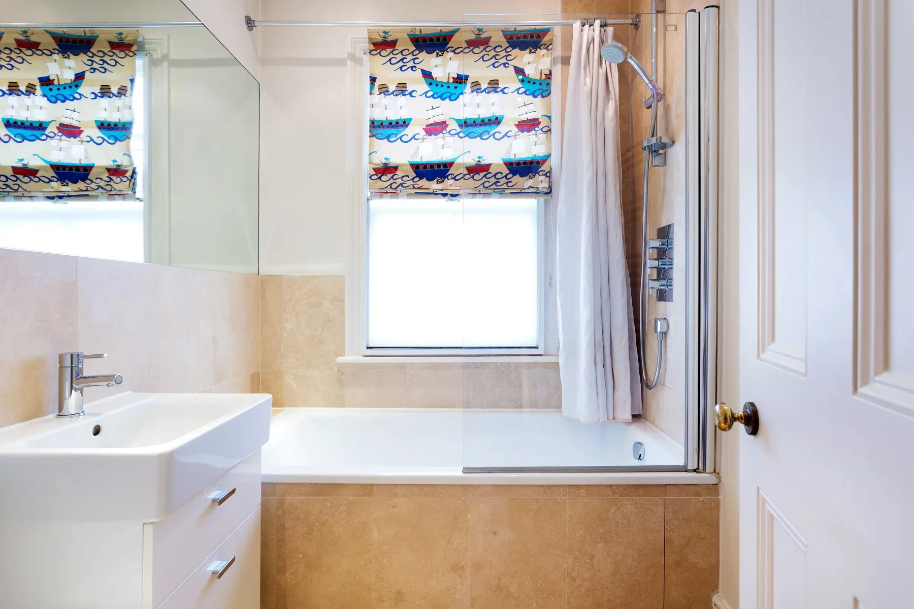A bathroom with a bathtub, shower, and sink beneath a window.
