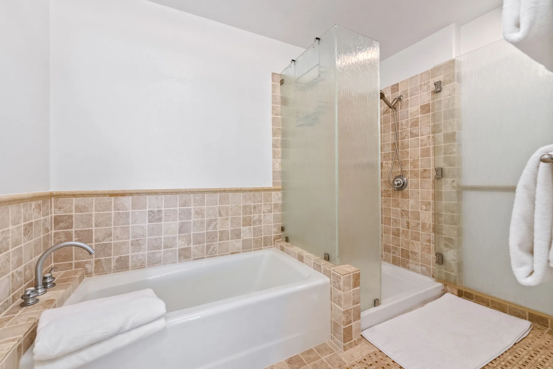 Un baño con azulejos, una bañera y una mampara de ducha de vidrio.