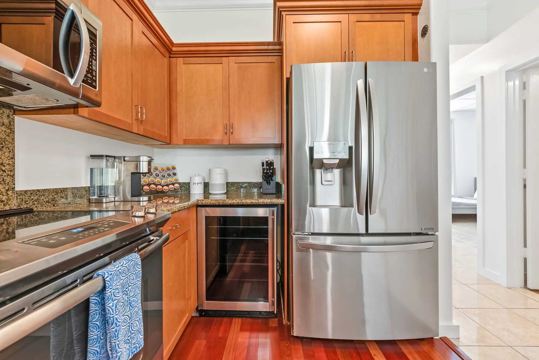 Una cocina con gabinetes de madera, electrodomésticos de acero inoxidable y piso de baldosas.