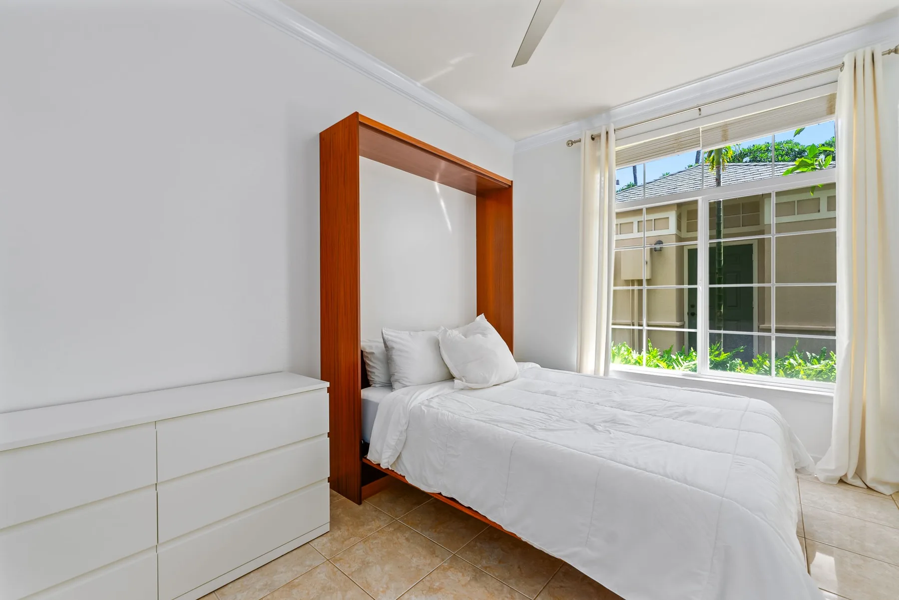 Un dormitorio luminoso con una cama y una ventana grande.
