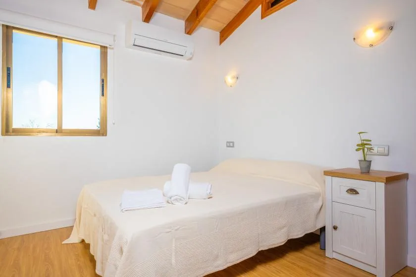 A bedroom with a bed, a window, and a small bedside cabinet.