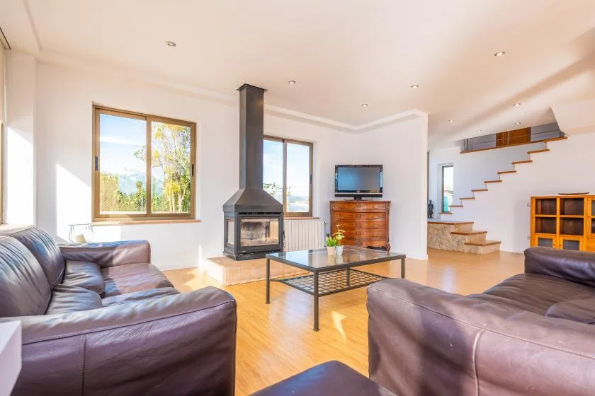 A bright living room with seating, a glass coffee table, and a fireplace.