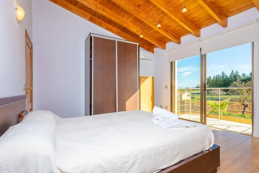 A bedroom with a large bed beside sliding glass doors opening onto a balcony.