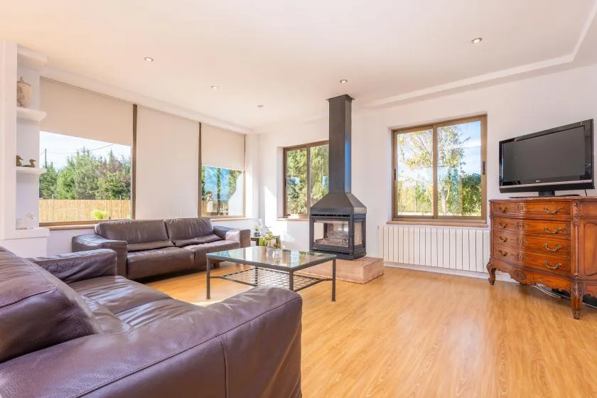 A bright living room with leather seating, a glass coffee table, and a fireplace.