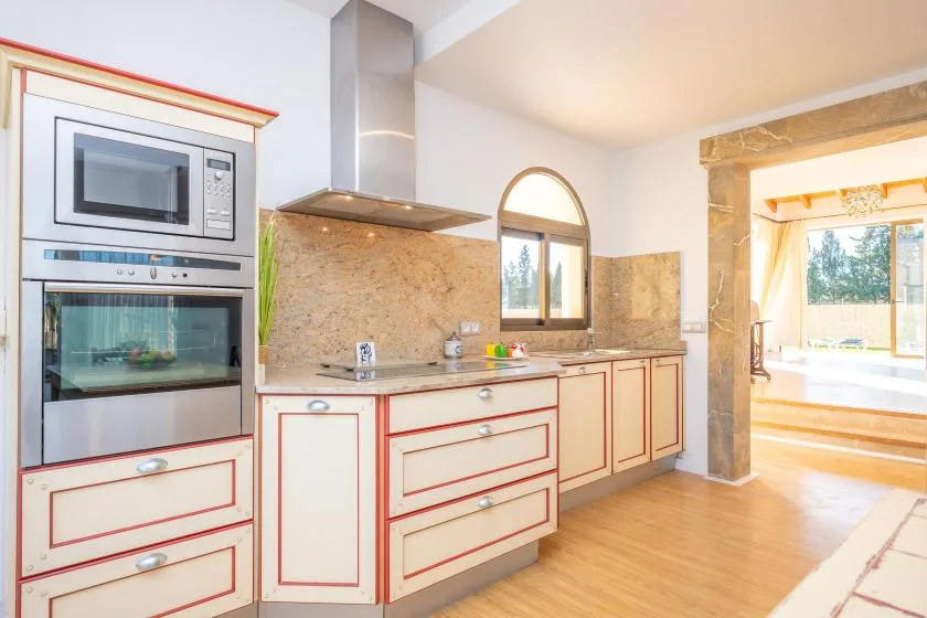 A bright kitchen with built-in appliances, counters, and a window.